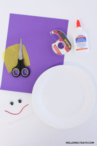 A paper plate, glue, tape and tape are laid out for a Ramadan craft.