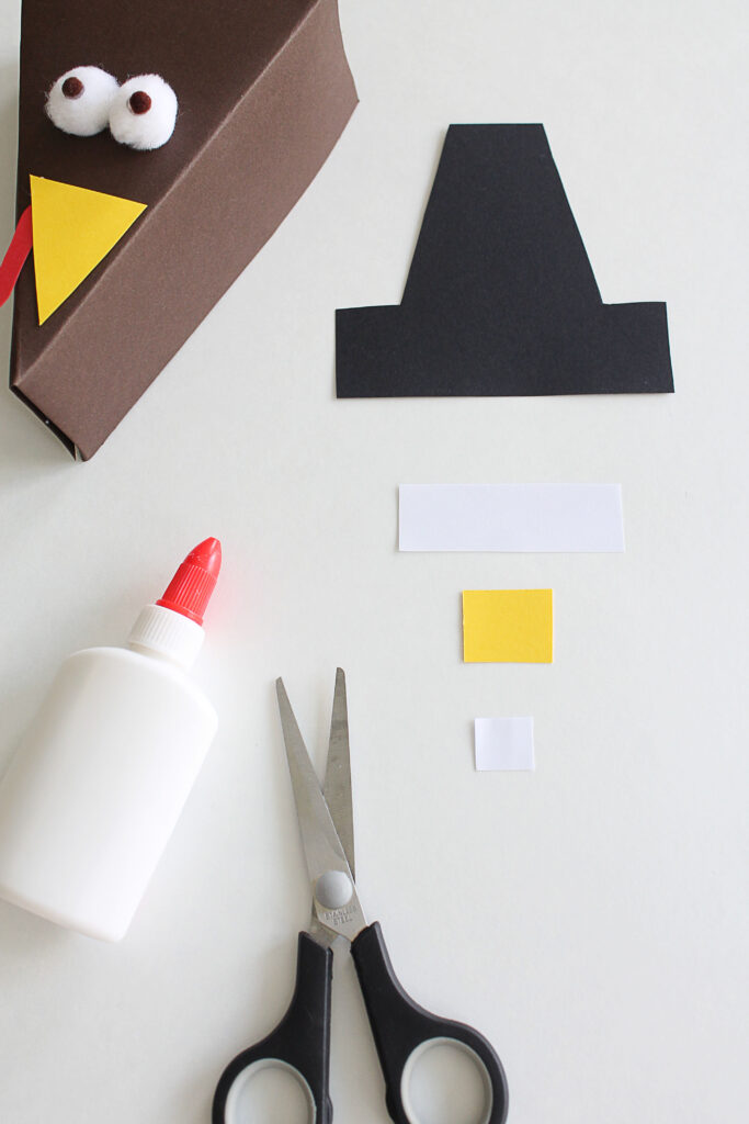 Make a Thanksgiving pilgrim hat with paper and glue. 